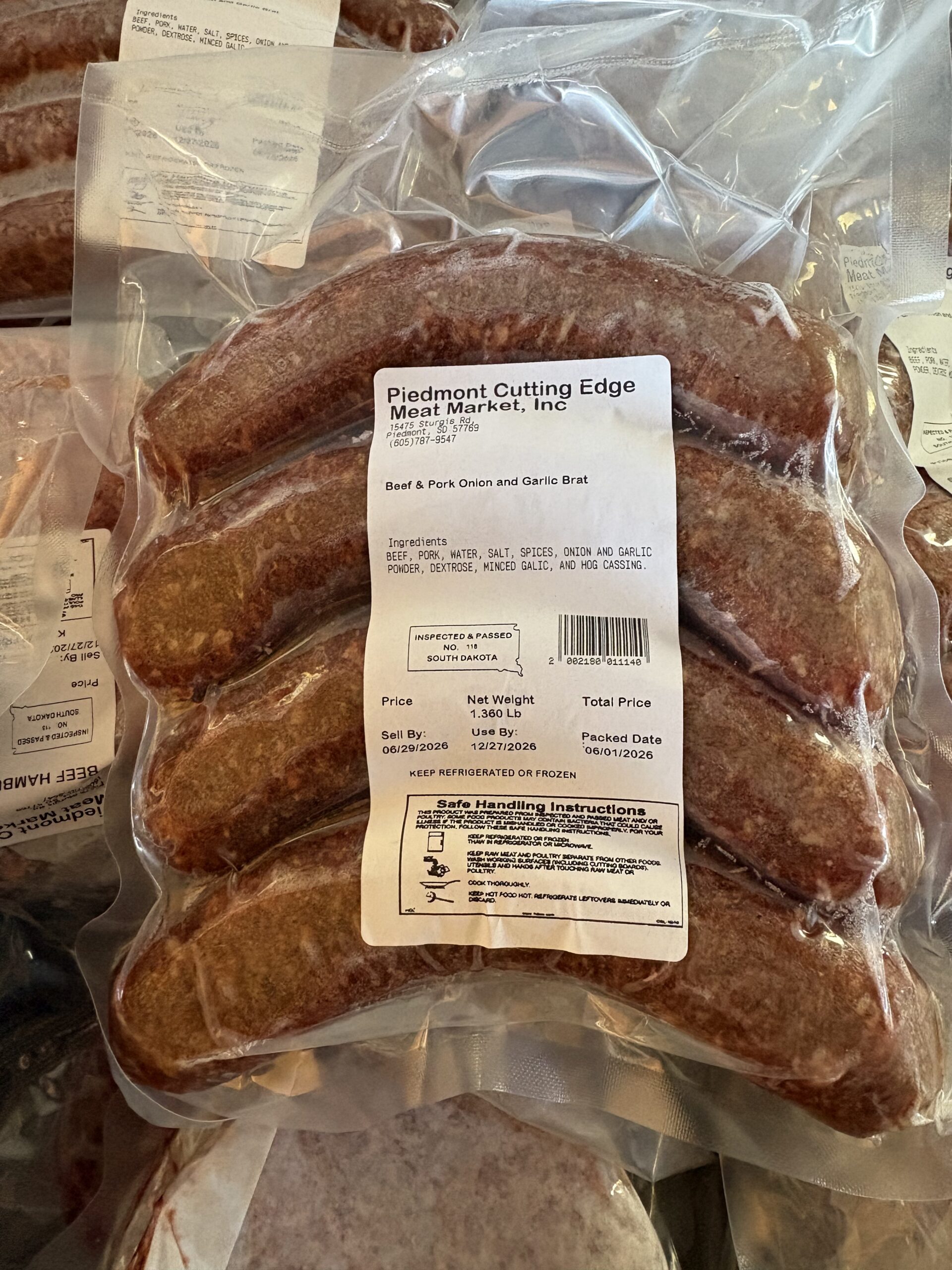 Beef and pork onion and garlic bratwurst packaged from Piedmont Cutting Edge Meat Market, featuring ingredient details and handling instructions. The package shows a net weight of 1.360 lb with sell and use-by dates.